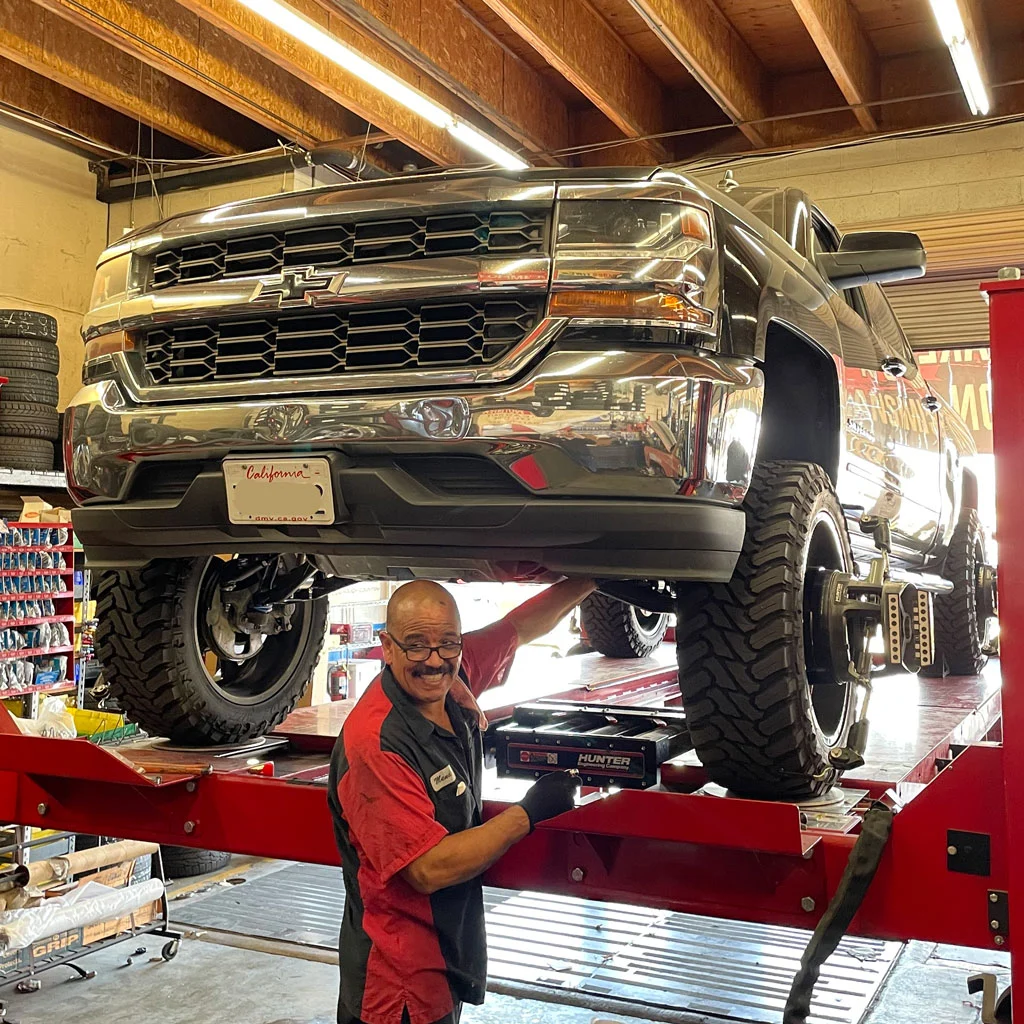 Mechanic Performing A Wheel Alignment On A Chevy Lifted Truck